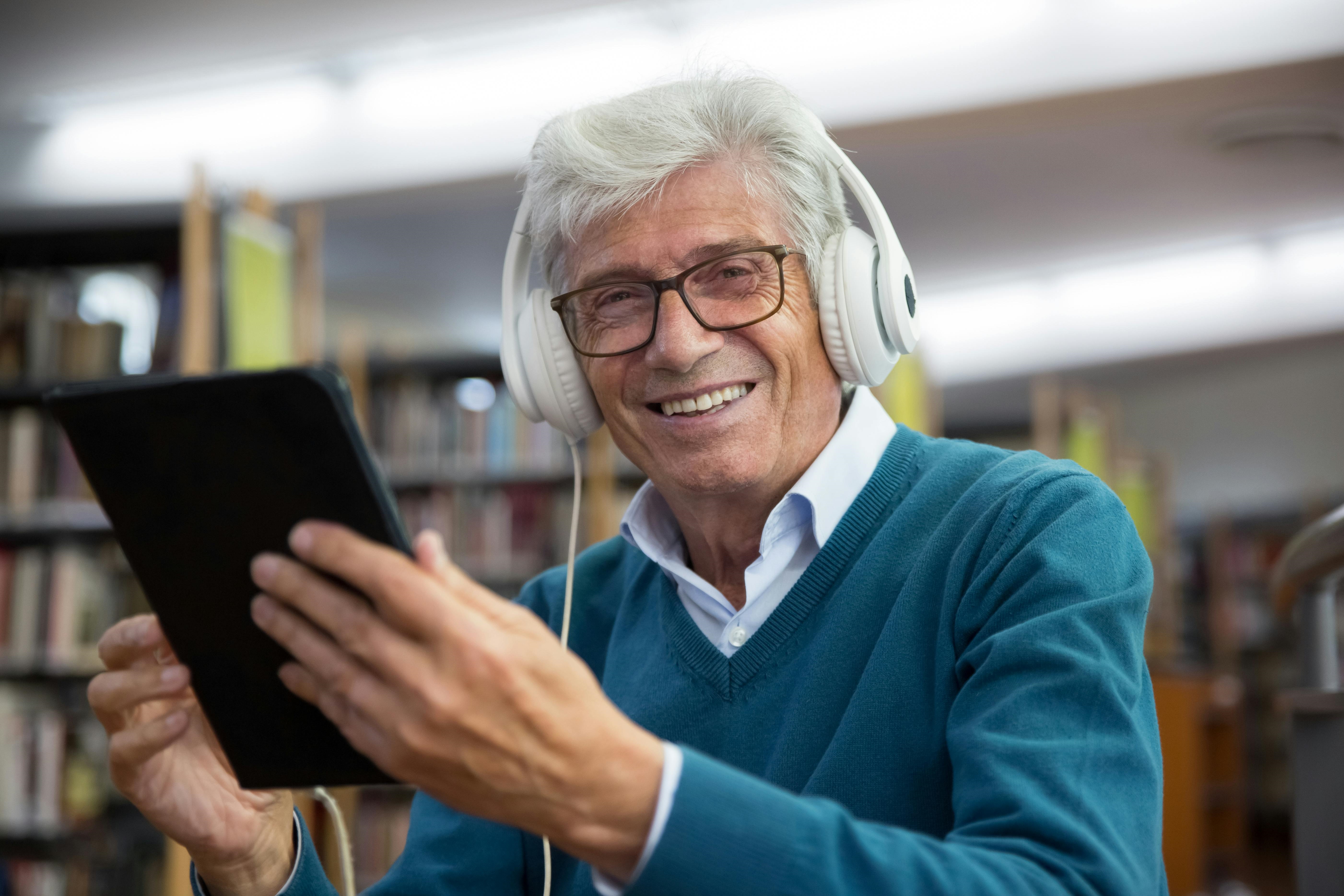 Older person with headphones and ipad.